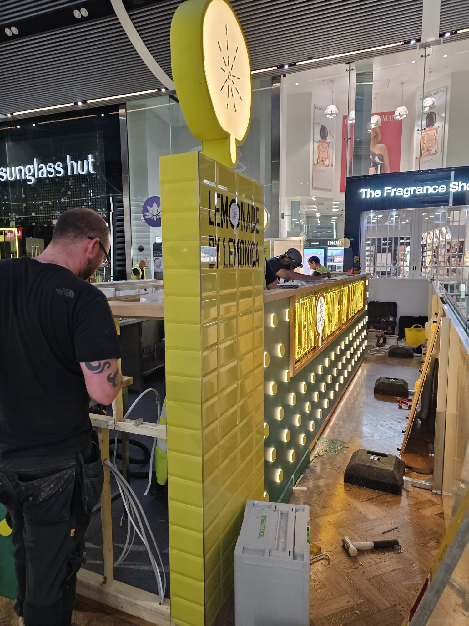 OLLYWOOD fitter installing the Lemonica kiosk counter and illuminated fascia at Westfield Stratford